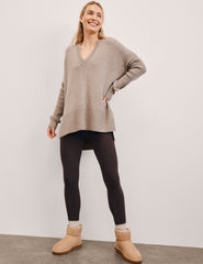 Woman wearing a beige v-neck sweater against a plain background.