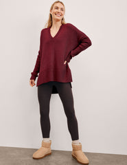 woman wearing a red v-neck sweater sweater against a plain background.