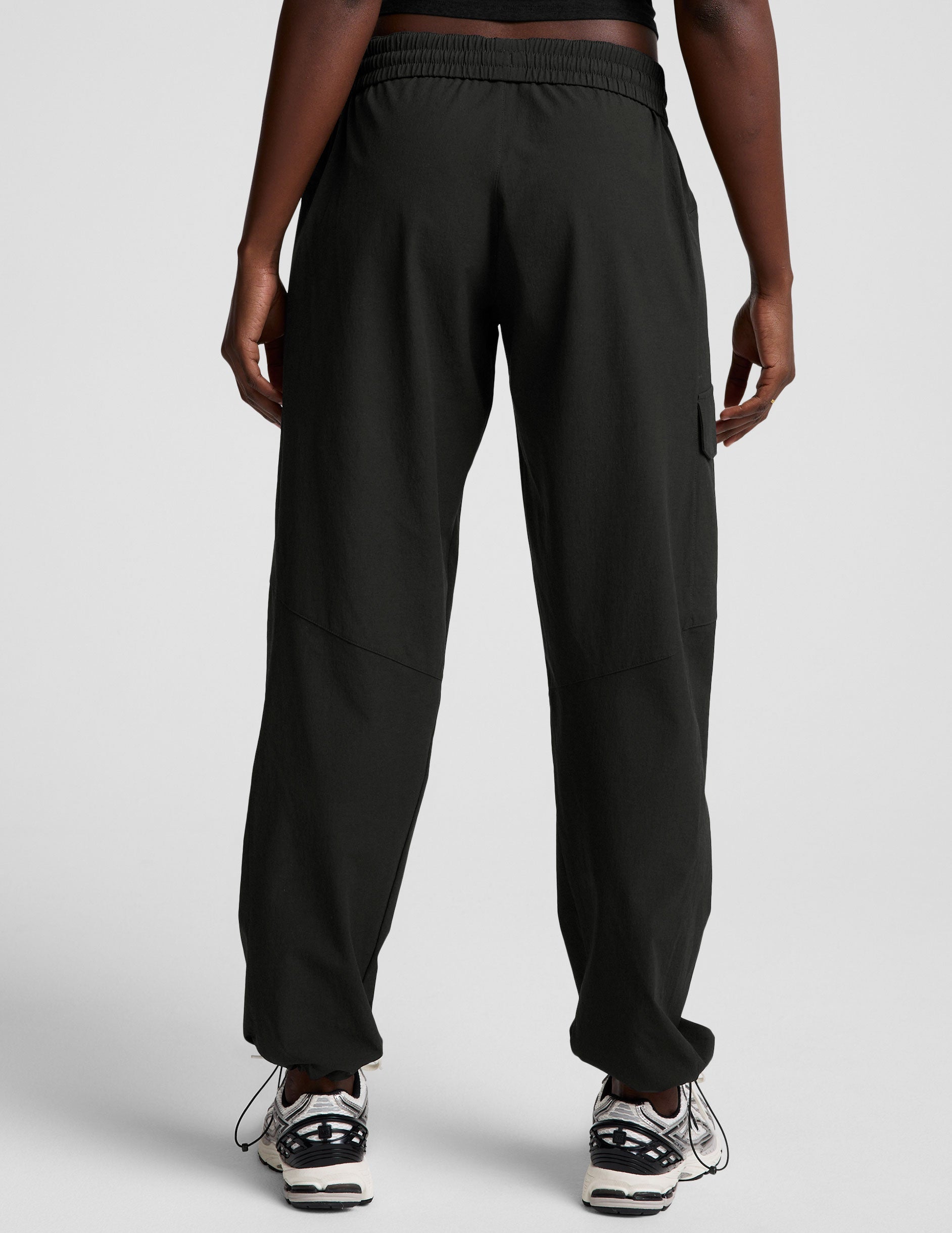 model wearing a black t-shirt and black cargo style pants on a white background.