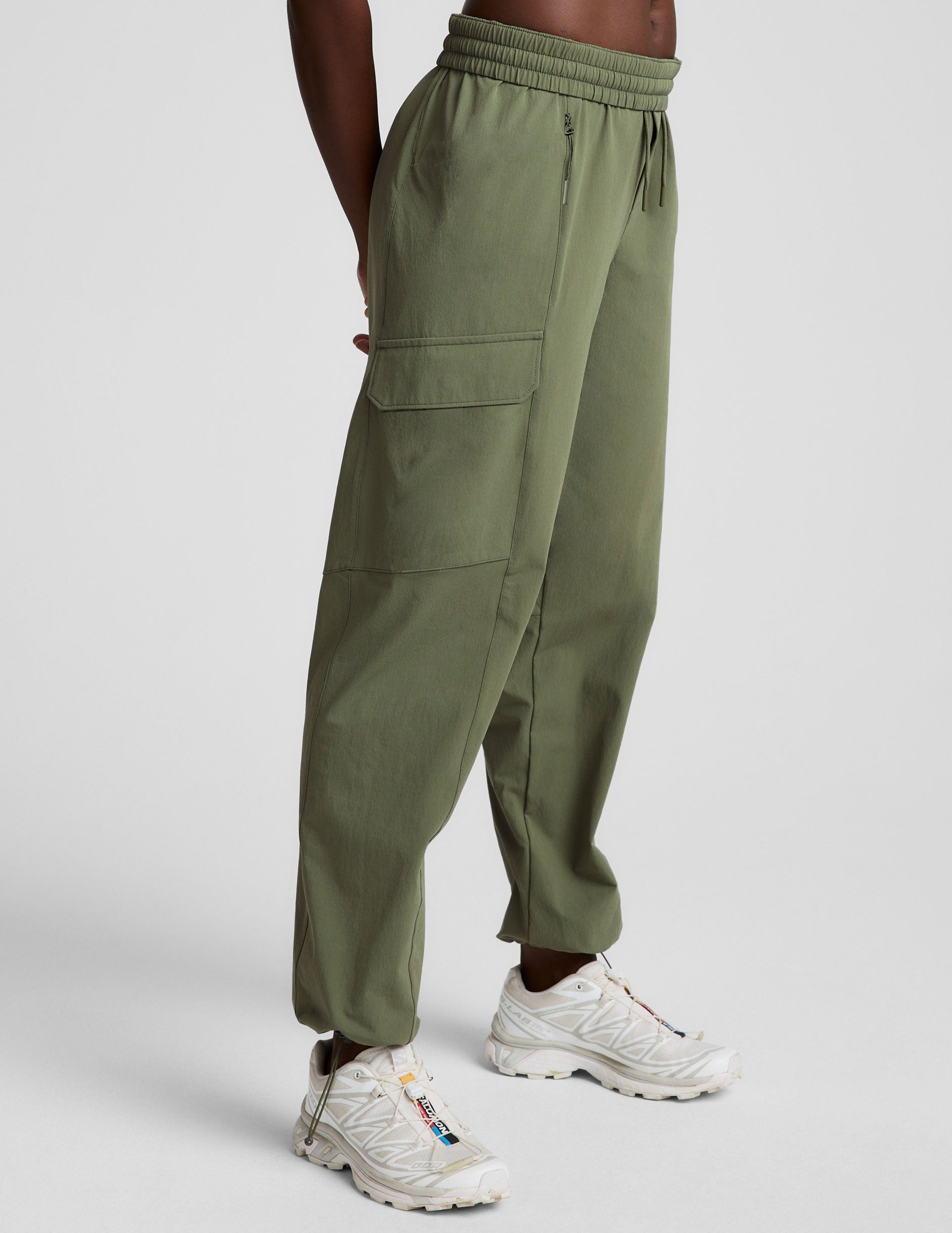 model wearing olive green cargo pants on a white background.