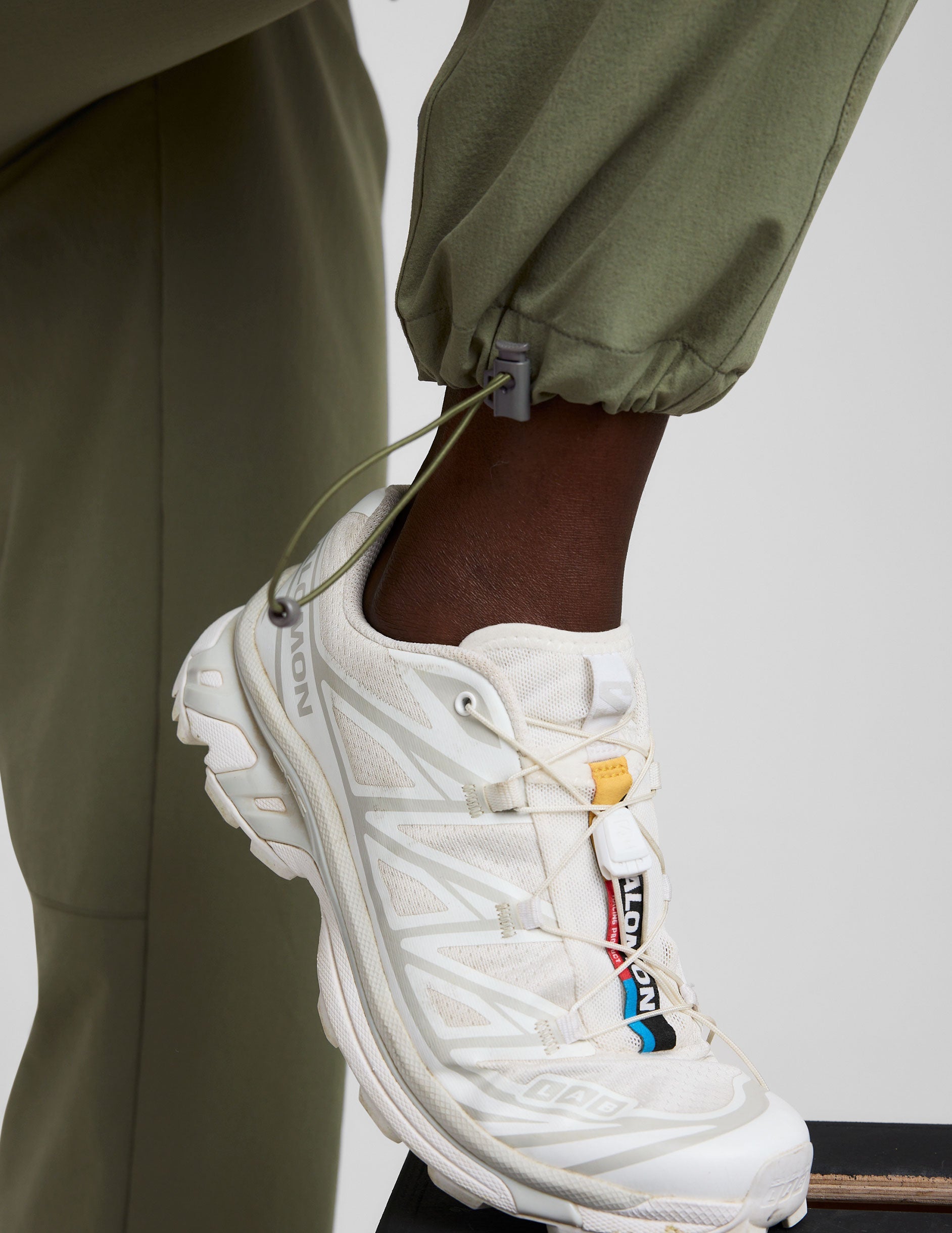 white sneaker with colorful accents worn by model in green cargo pants against a neutral background.