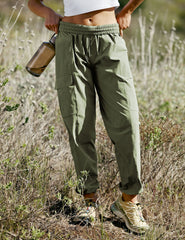 model wearing a white t-shirt and green cargo style pants walking on a trail in nature wearing a white top and green pants.