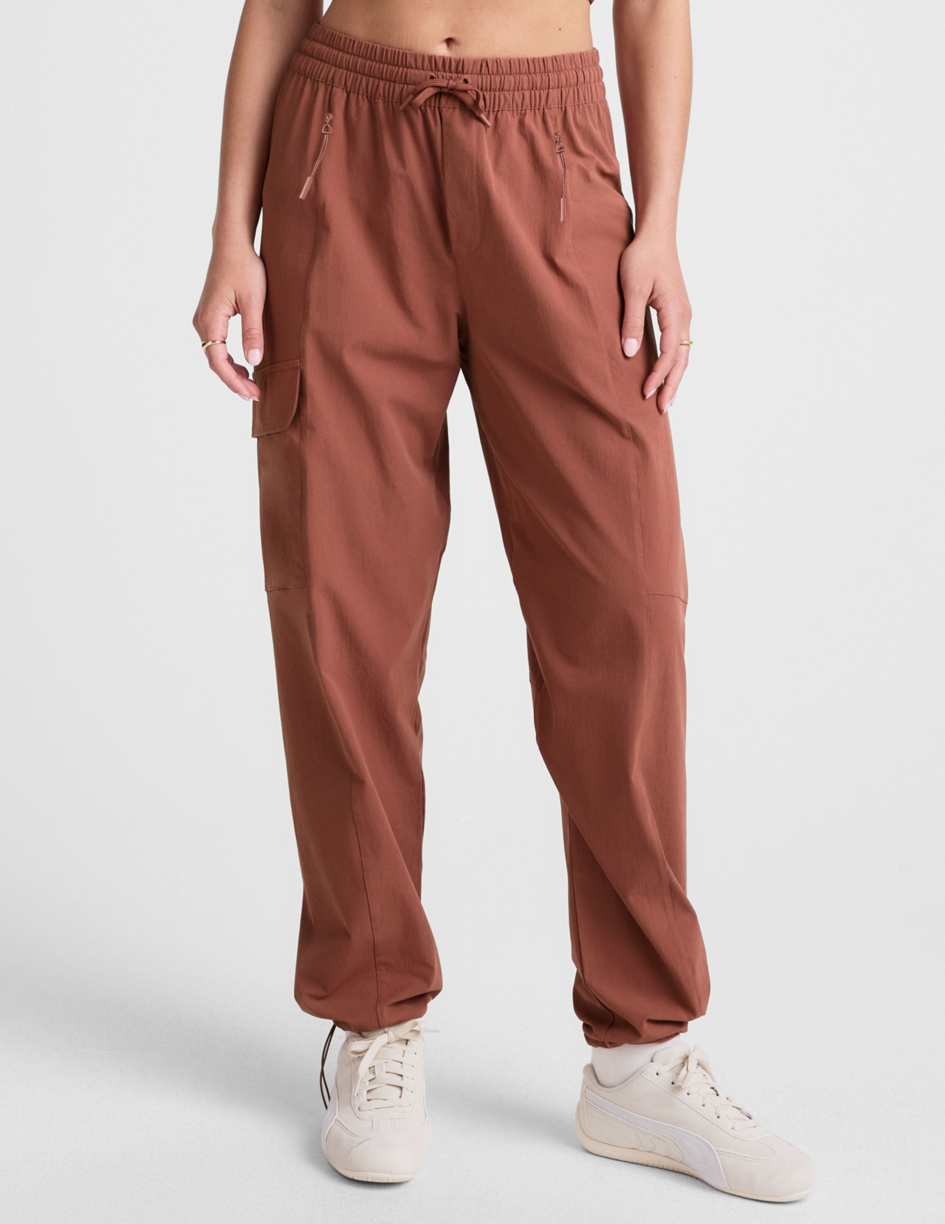 model wearing an orange ribbed tank top and orange cargo pants on a white background.