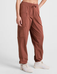 model wearing an orange ribbed tank top and orange cargo pants on a white background.