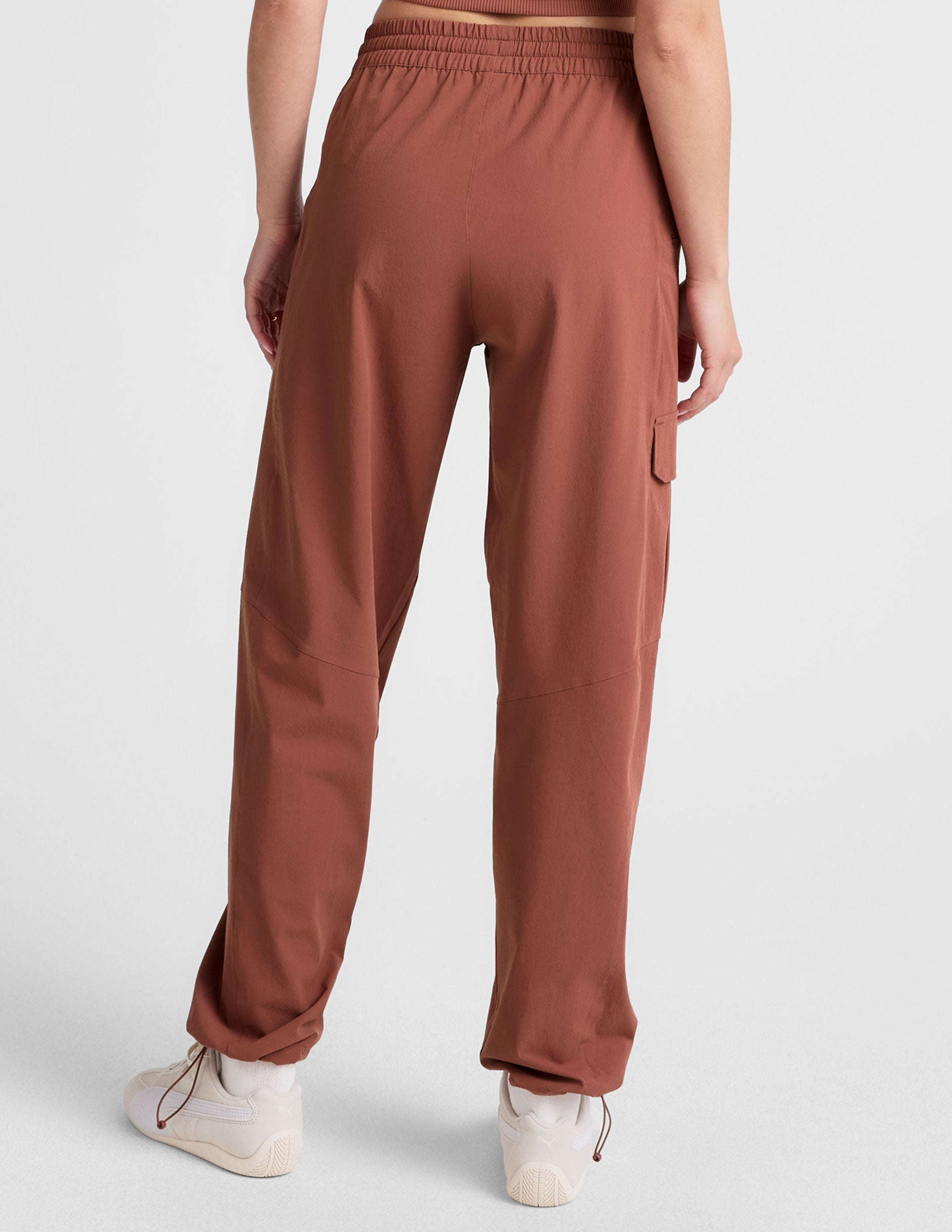 model wearing an orange ribbed tank top and orange cargo pants on a white background.