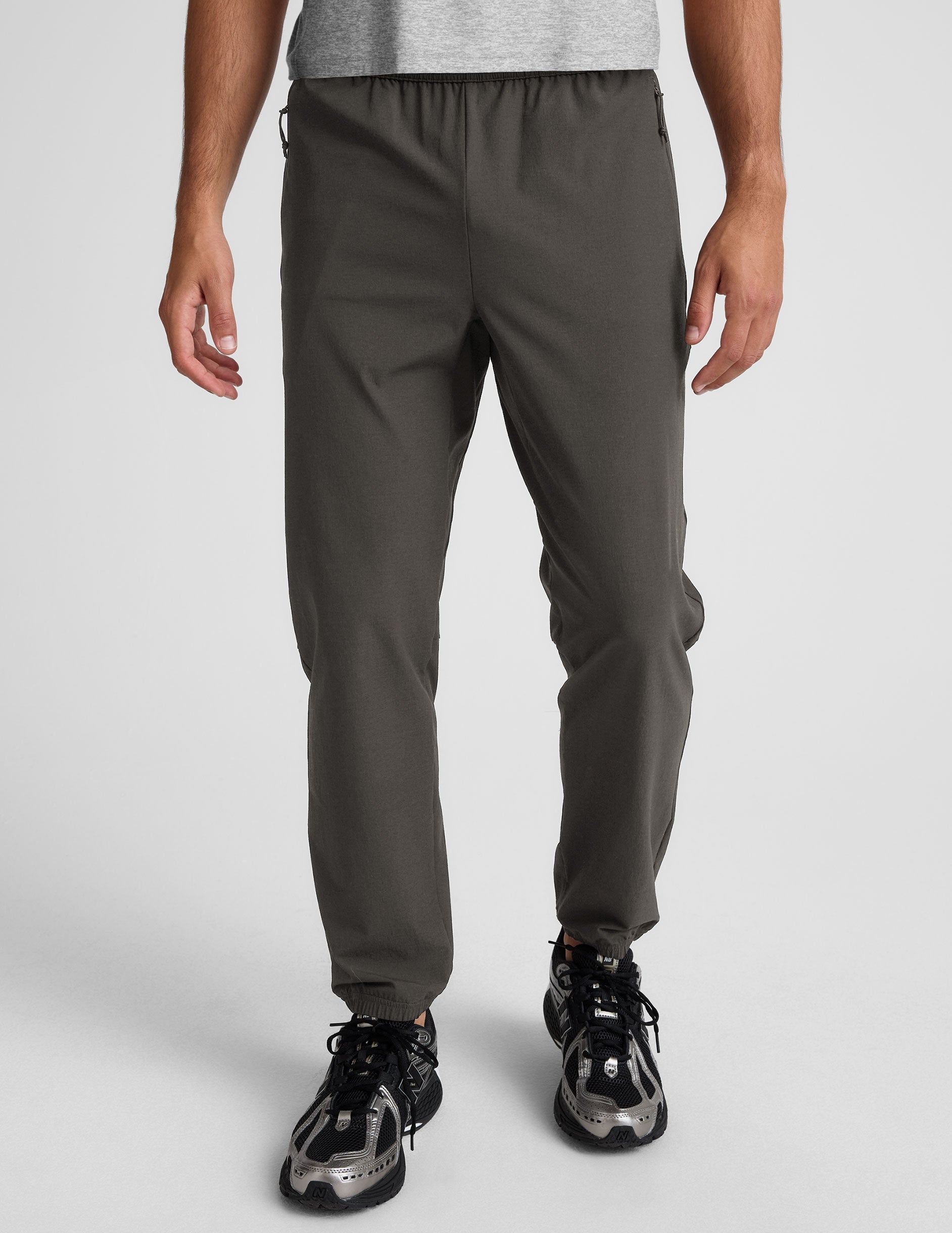 dark gray joggers and a grey t-shirt on a plain background.
