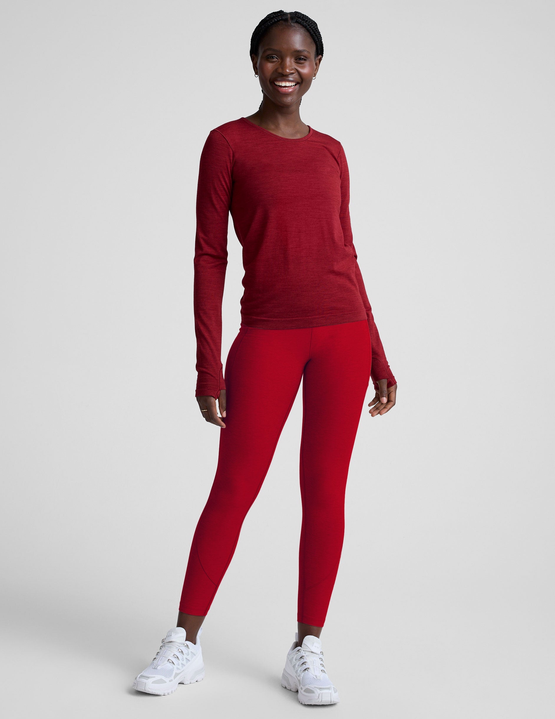 woman wearing a red long-sleeve top and red leggings on a plain background.