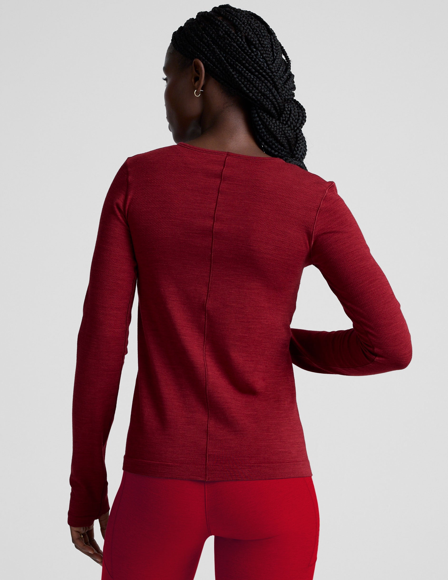 woman wearing a red long-sleeve top and red leggings on a plain background.