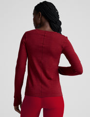 woman wearing a red long-sleeve top and red leggings on a plain background.